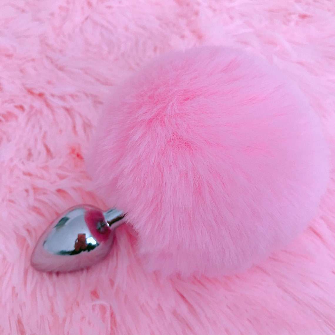 A pink bunny tail butt plug with a detachable stainless steel plug